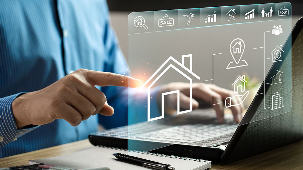Eine Person arbeitet am Laptop und bedient eine transparente Oberfläche mit Immobilien-Symbolen. Die Darstellung zeigt digitale Funktionen rund um Haus und Verkauf.